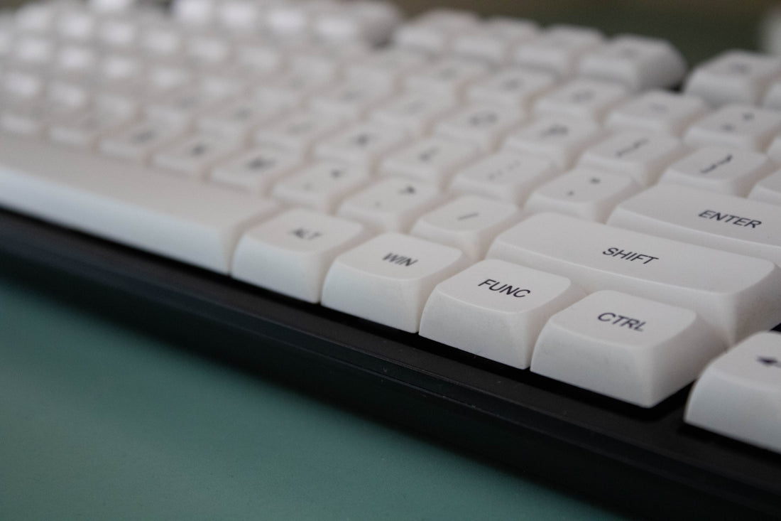 White mechanical keyboard close-up on a light green surface.