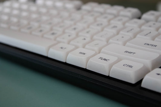 White mechanical keyboard close-up on a light green surface.
